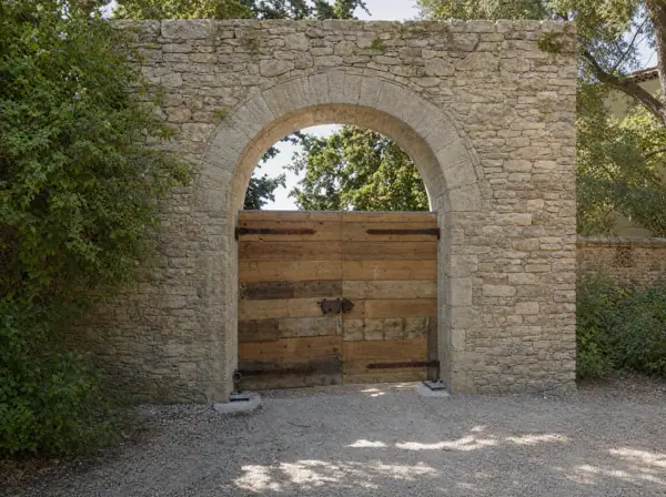 Portail en vieux pin à sangles de fer sous une arche de pierre, ferronnerie ancienne