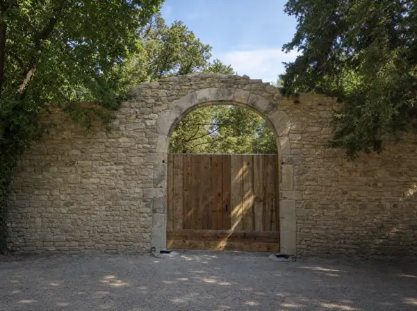 Portail en vieux pin sous une arche de pierre